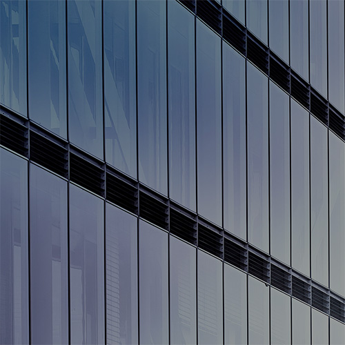 Why EAM Works Better as a Digital Twin for Enterprises. Close-up of a modern glass building with vertical panels and black louvers.