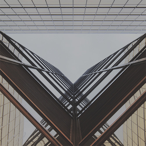 Why EAM Works Better as a Digital Twin for Enterprises. Upward view between two glass skyscrapers forming a V-shape against the sky.