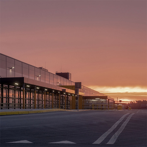 From warehouse cost center to growth engine. Modern warehouse at sunset with loading bays and glass exterior.