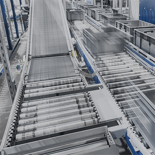 Automated warehouse conveyor system transporting plastic bins in a modern logistics facility.